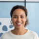 Headshot of a smiling woman, late 20s, with a diverse background, conveying trust and satisfaction.